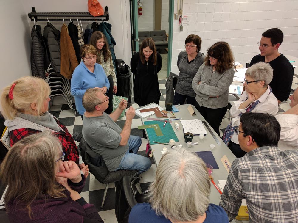Instructor Rick Draffin illustrates writing in bleed-proof white around an angle bend on matte paper