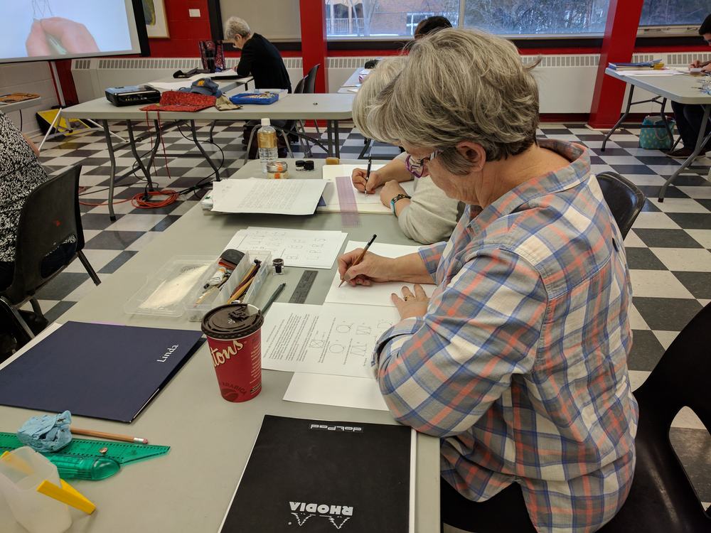 Students following along with the overhead and handouts to learn the proportions of monoline Roman letters